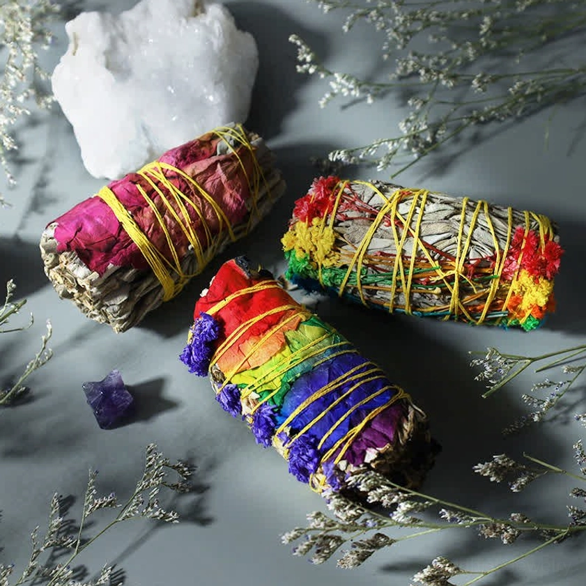 Flat lay arrangement of smudge stick bundles with crystals and dried herbs in spiritual cleansing setup