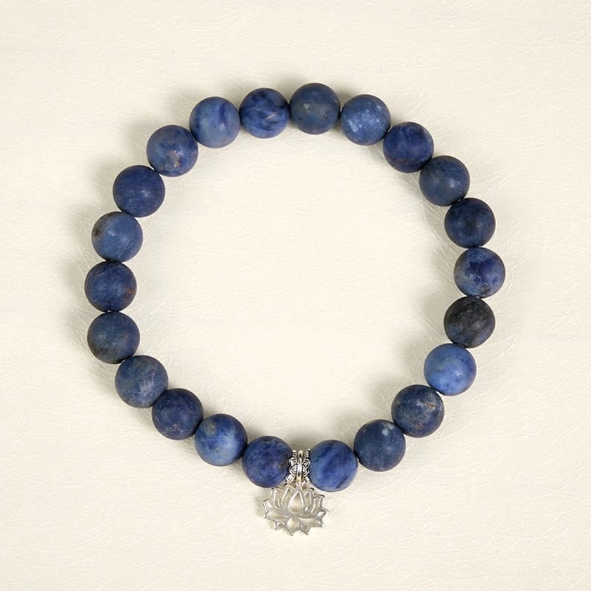 Top view of sodalite beaded bracelet featuring 8mm blue matte stone beads and hollow silver lotus pendant on white background