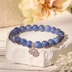 Sodalite lotus bracelet with 925 sterling silver charm displayed with natural stone and flower props - Buddhist harmony beads