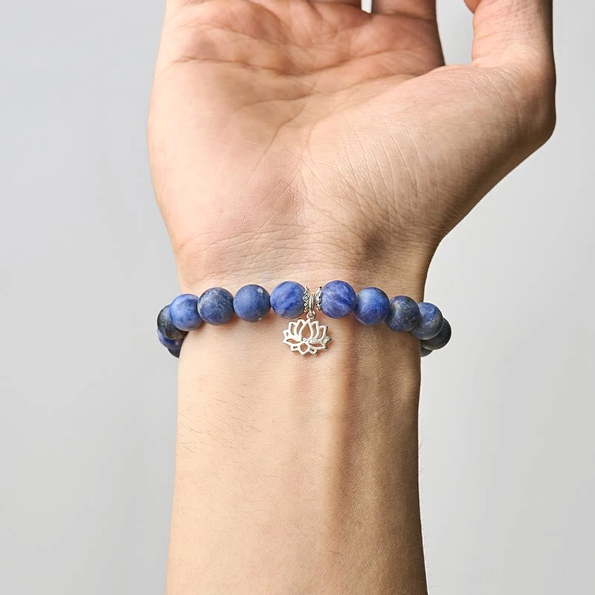 Close-up of sodalite lotus bracelet worn on human wrist showing 8mm blue stone beads and silver lotus pendant in real wear