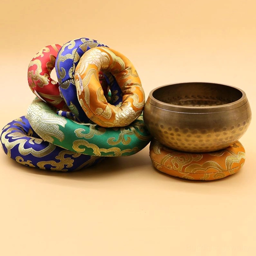 Multiple Buddhist singing bowl meditation cushions arranged with a singing bowl resting on decorative brocade base