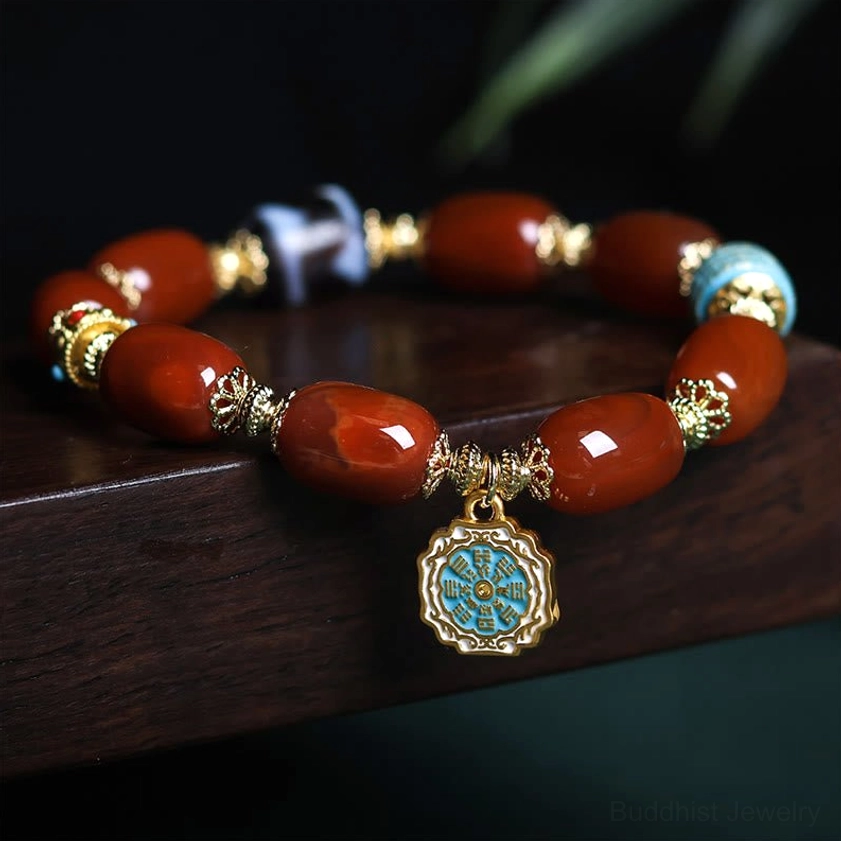 South Red Agate Bagua Dzi Bead Bracelet - side angle view showing barrel-shaped red agate beads with gold-plated fittings and Bagua charm pendant