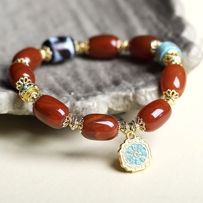 South Red Agate Bagua Buddhist Bracelet on grey stone mat background showing barrel beads and blue striped spacer details