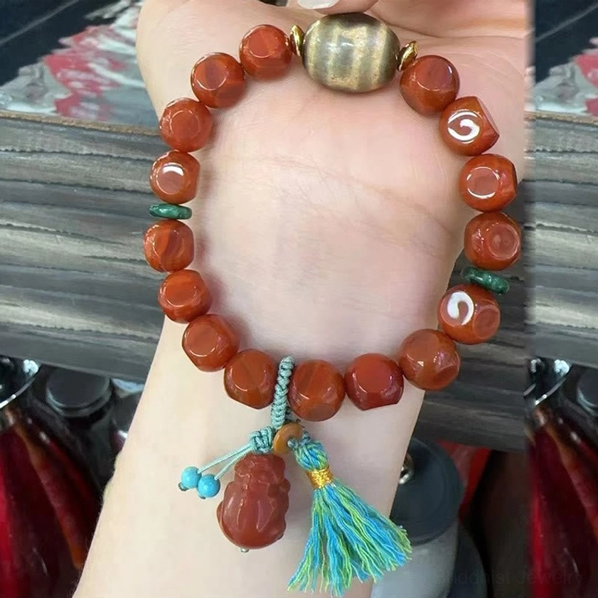 South Red Agate Pixiu bracelet worn on hand showing faceted red beads, teal tassel charm and brown central bead