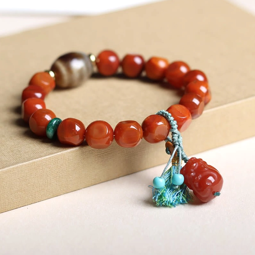 South Red Agate prosperity bracelet with round smooth red beads, teal spacer beads, and Pixiu tassel on cardboard display