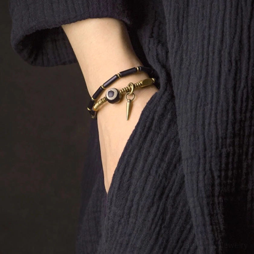 Single wrap black onyx Dzi bead bracelet on wrist with layered companion bracelet styling