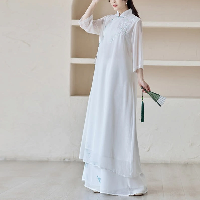 Mindful practice wear set with cheongsam dress and wide leg pants, front-side angle with model holding traditional folding fan with green tassel trim