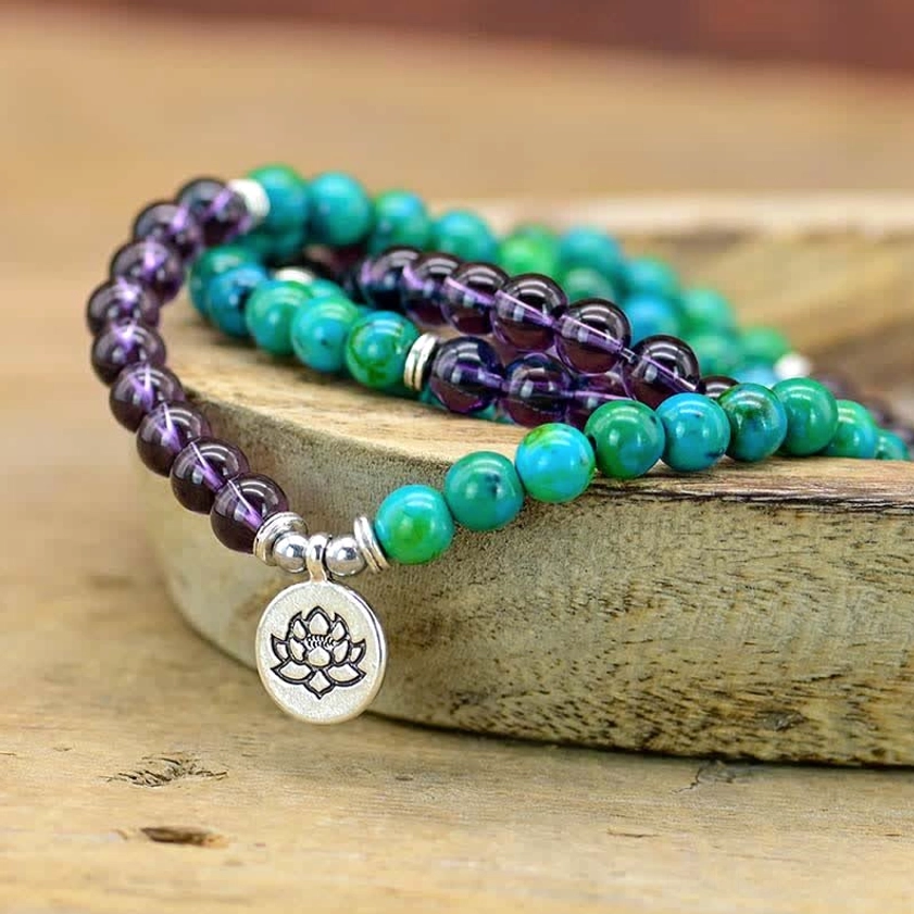 Handmade lotus charm bracelet featuring polished amethyst and green aventurine beads stacked in rustic wooden bowl