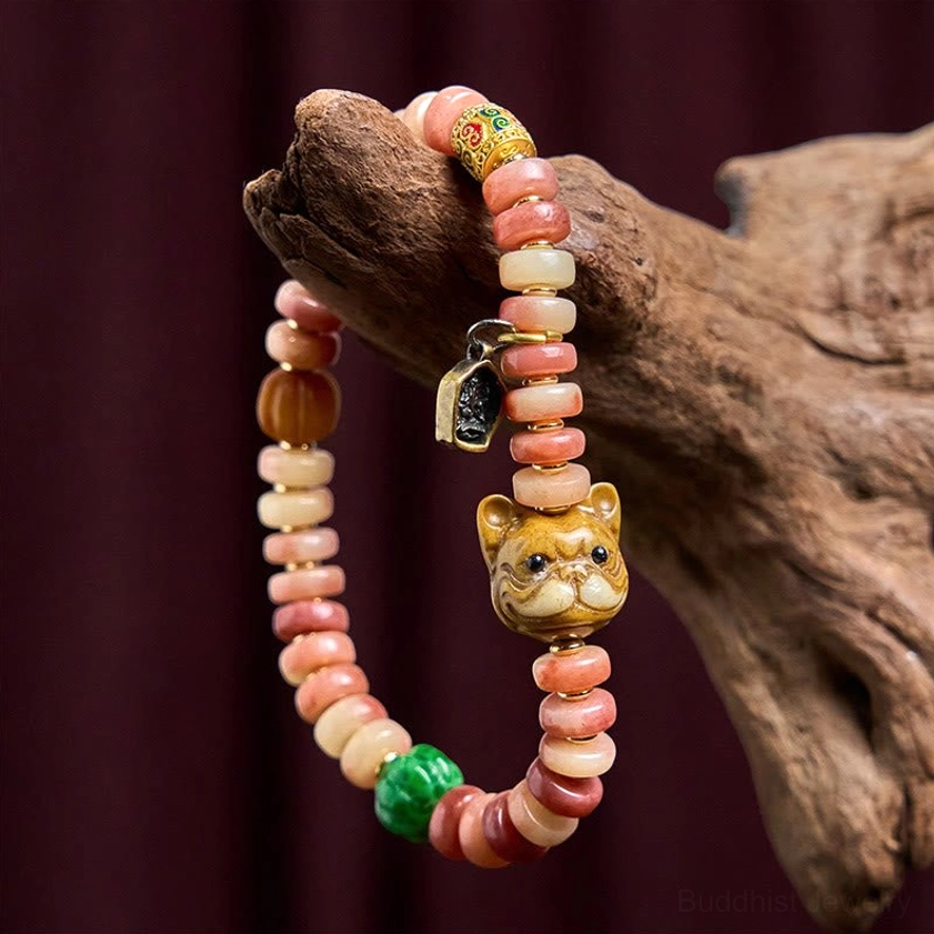 Natural camel bone pug luck bracelet with wooden background prop, showing pink-cream gradient beads and metal charm details