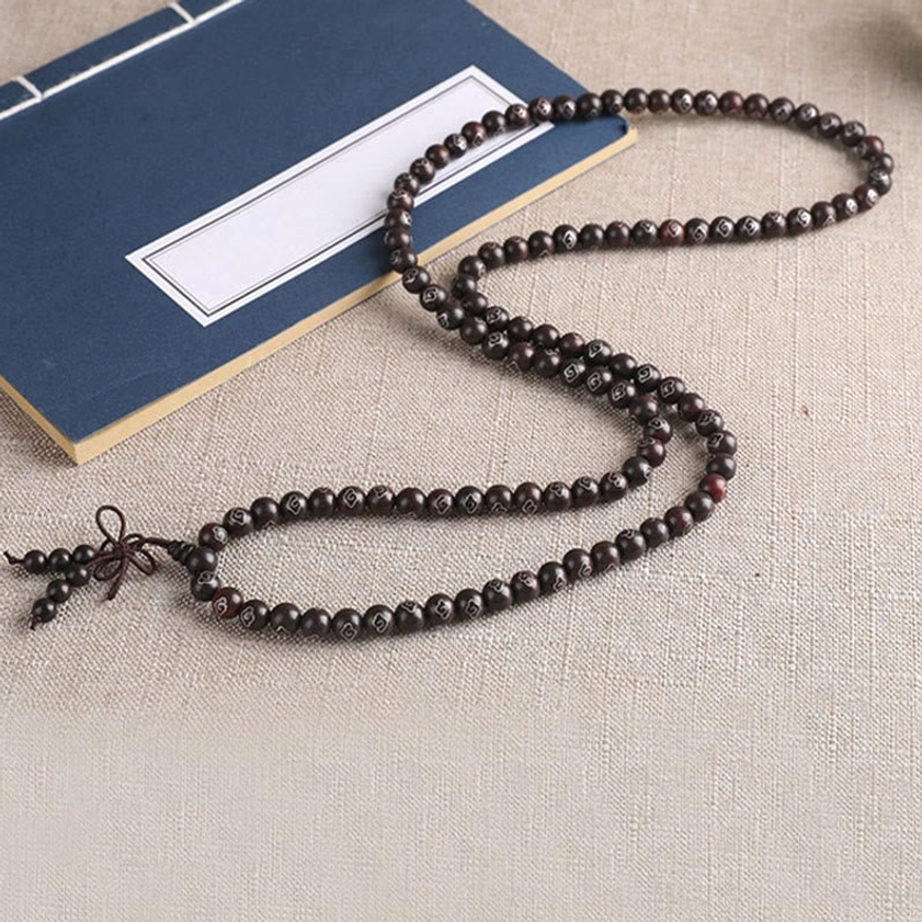 Spiritual red sandalwood bracelet featuring Om Mani Padme Hum mantra with polished wood grain and protective silver symbols