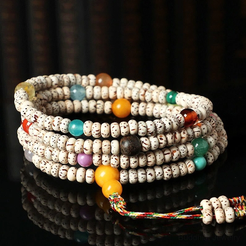 Stacked bodhi seed prayer bead sets with star-moon seeds and gemstone accents on dark reflective tabletop