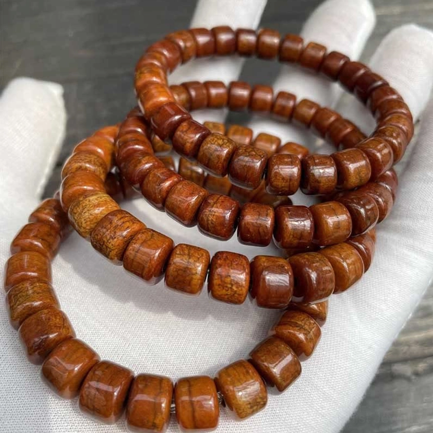 Stacked bone bead bracelets multiple strands with natural matte texture on wooden table