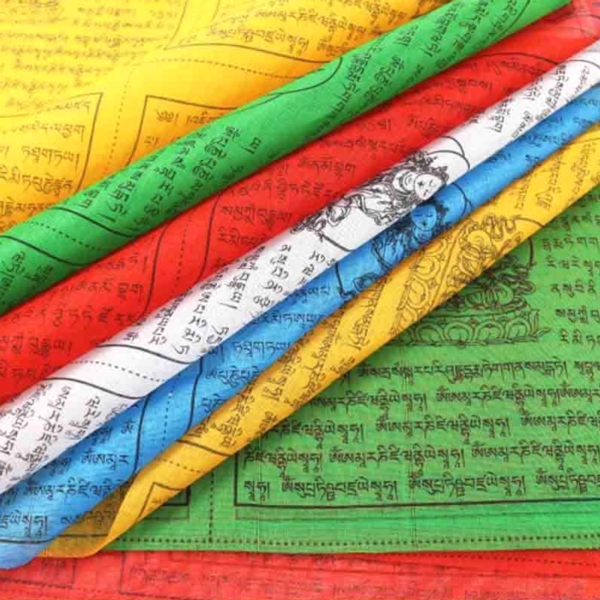 Stack of hand-printed Buddhist prayer flags showing all five sacred colors Pancha Mahabhuta with traditional Tibetan mantras and Buddhist patterns clearly visible