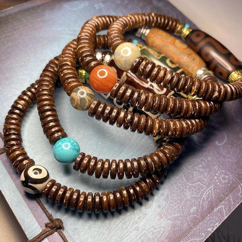 stacked layered nine-eye dzi bead bracelets in various colors and patterns demonstrating versatile styling and yin-yang symbolism