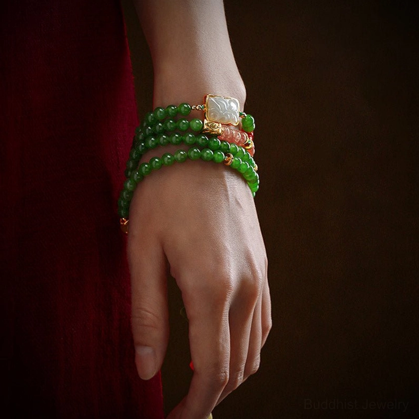 Stacked multiple jade mala bracelets on wrist with metal spacers and jade decorations