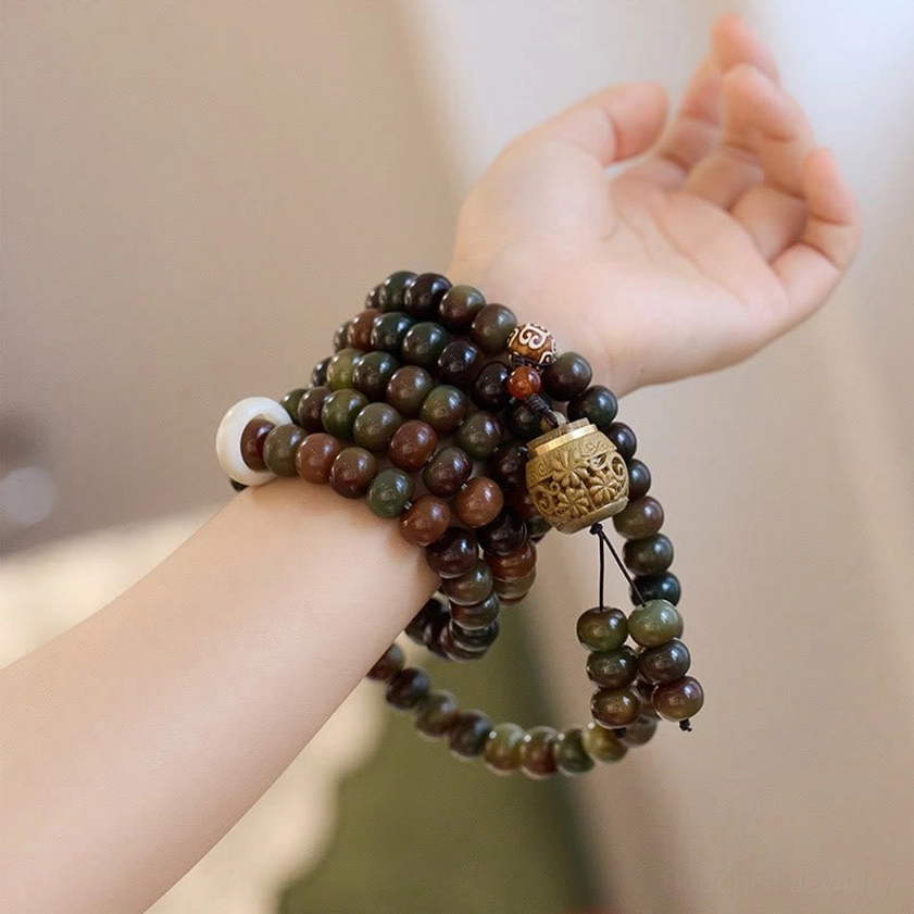 Stacked mala prayer beads worn on wrist, close-up shot showing mixed brown and green Bodhi seed beads with white spacer and pendant