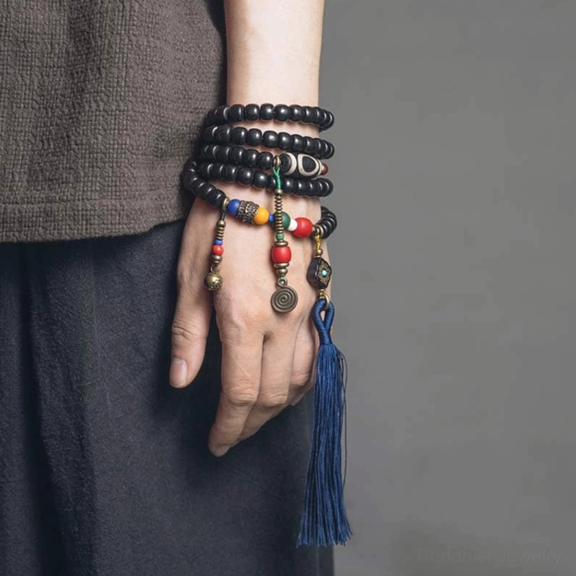 Stacked 108 bead mala bracelets with colorful decorative beads and brass pendants on hand