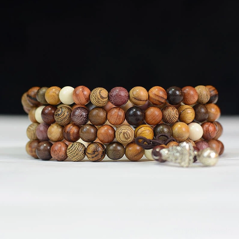 Stacked natural wood mala beads looped strands with silver decorative pendants on white background, front close-up flat lay