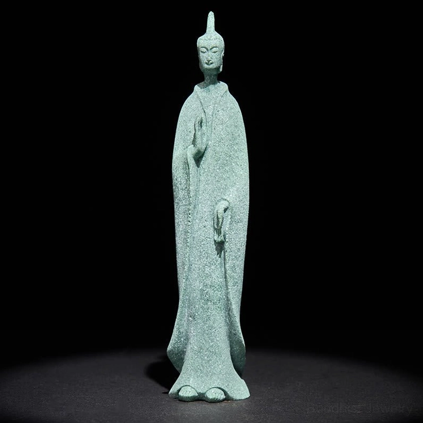 Buddha standing statue with calm facial expression and traditional flowing robe design studio shot