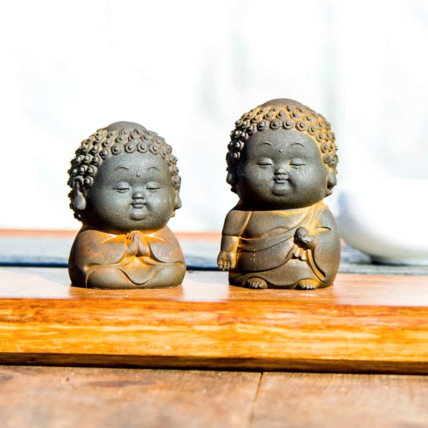 Two standing Buddha figurines with different meditation hand mudra positions on decorative wooden tea tray