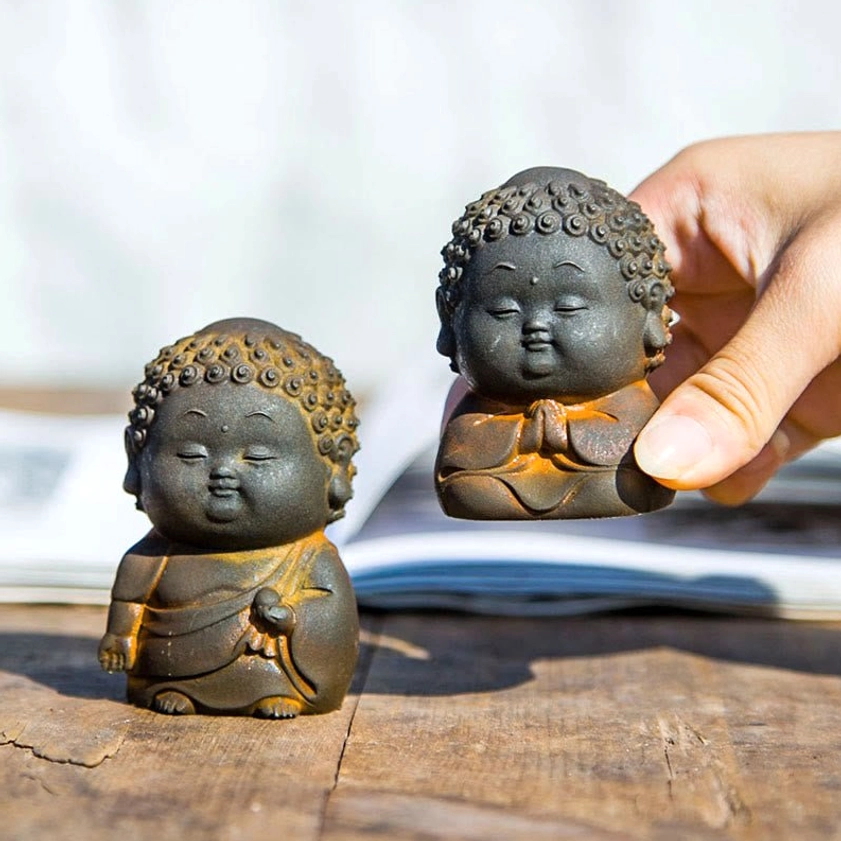 Two standing Buddha figurines with detailed hand positioning held and displayed on wooden surface
