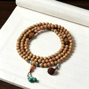 Star Moon Bodhi Seed 108 bead Buddhist prayer mala necklace with wooden lotus charm and turquoise tassel displayed on notebook