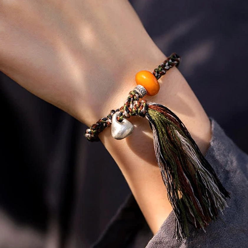 Woven cord protection bracelet inner wrist view showing silver drop charm and amber bead