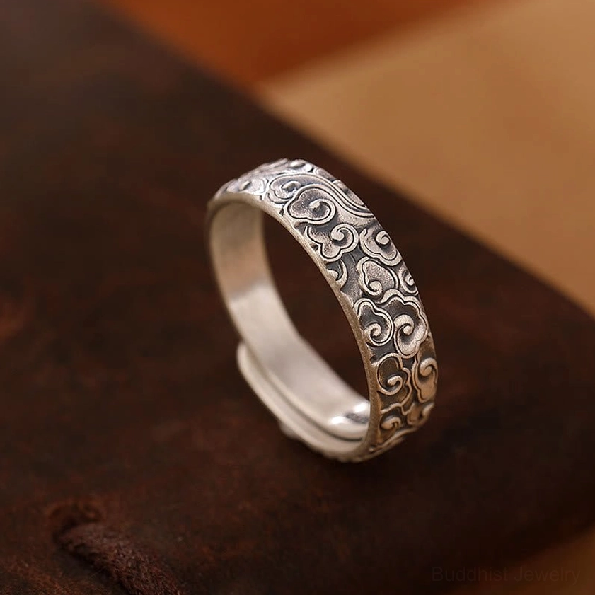 Auspicious clouds engraved sterling silver adjustable ring three-quarter view on dark brown leather with intricate cloud pattern design in antique silver finish