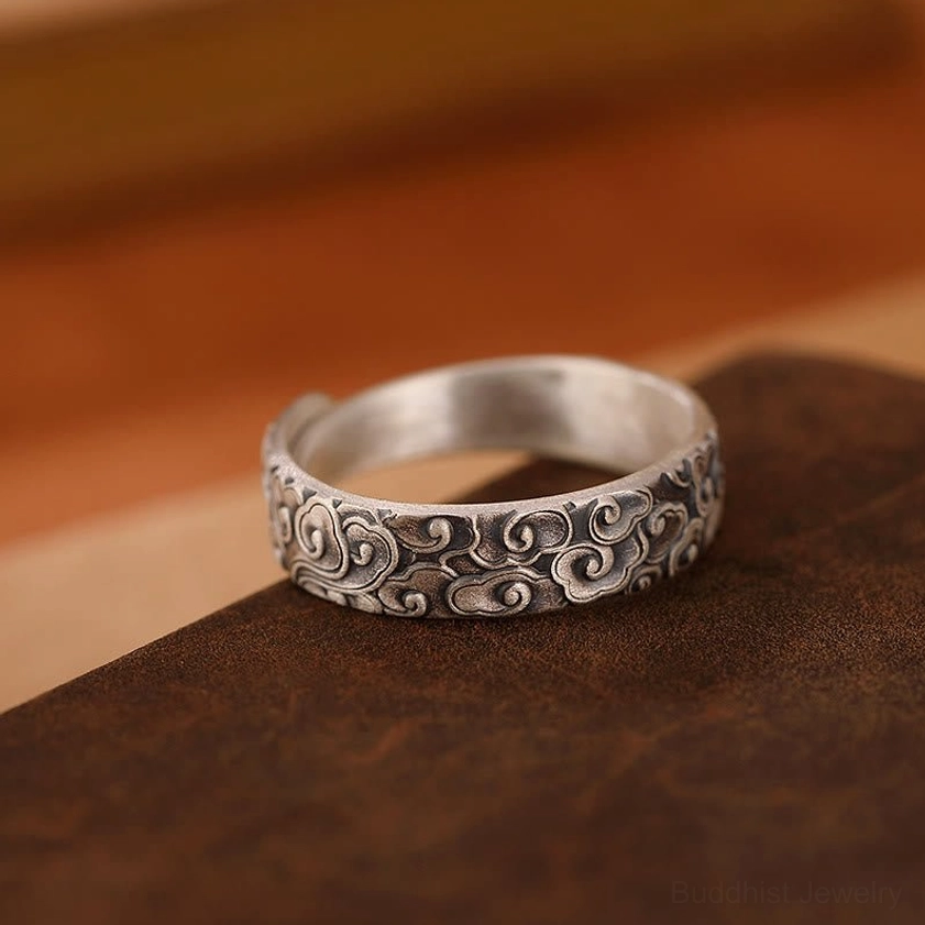 Auspicious clouds sterling silver adjustable open ring low side view on dark brown leather displaying full intricate cloud engravings and adjustable band structure