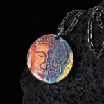 Sterling silver yin-yang Buddha demon pendant necklace with 24K gold trim displayed on volcanic stone, close-up view showing intricate dual-face engraving