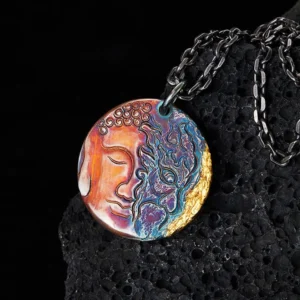 Sterling silver yin-yang Buddha demon pendant necklace with 24K gold trim displayed on volcanic stone, close-up view showing intricate dual-face engraving