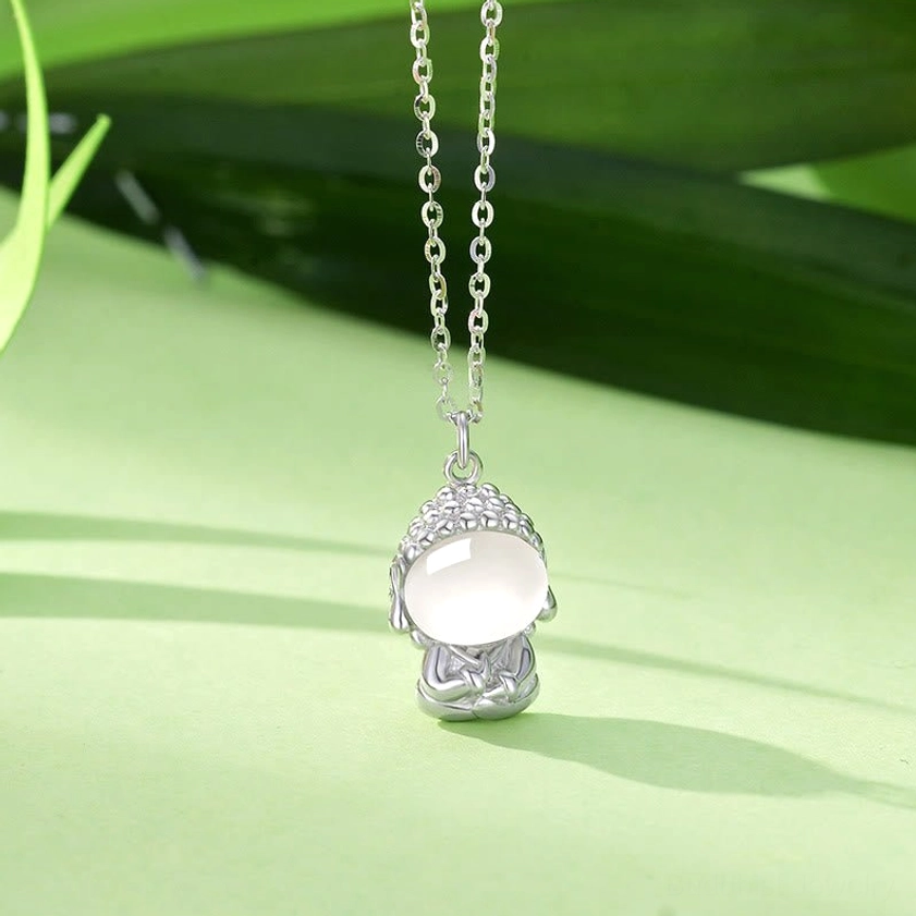 Sterling silver Buddha pendant necklace with white chalcedony stone and detailed Buddha design, studio photography with green leaf background