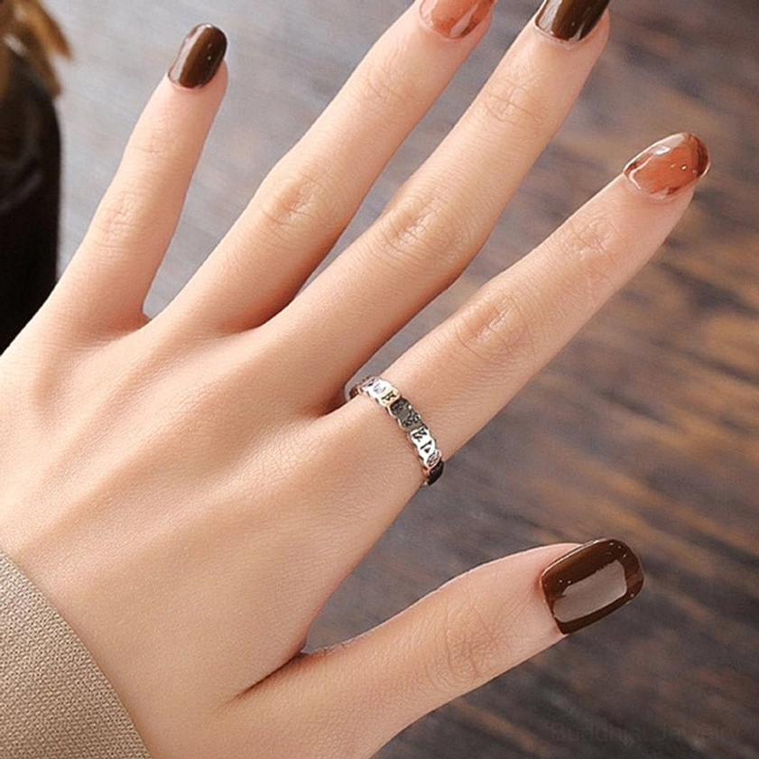 Sterling silver Buddhist mantra ring on finger - wearing demonstration on wooden table showing comfortable fit and elegant appearance