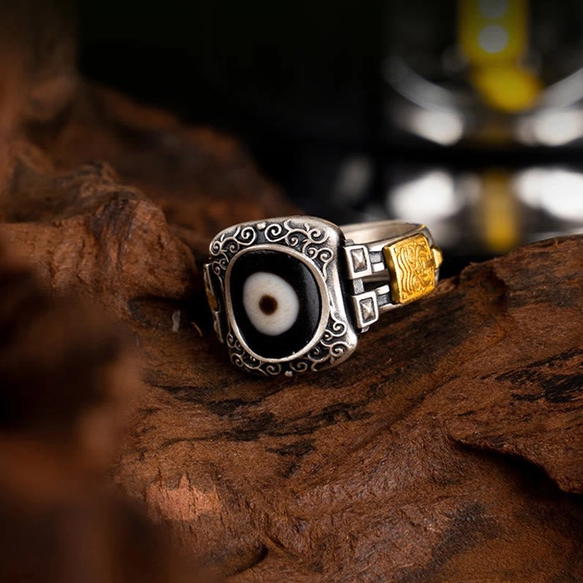 Sterling silver Dzi bead protection ring, compact scroll bezel design in side front angle view, spiritual Buddhist jewelry piece