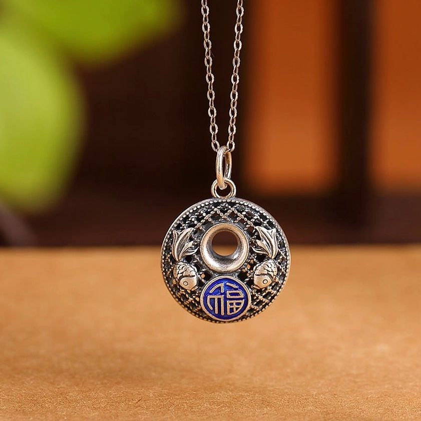 999 sterling silver koi fish fu character pendant with blue enamel detail front view on warm wooden backdrop