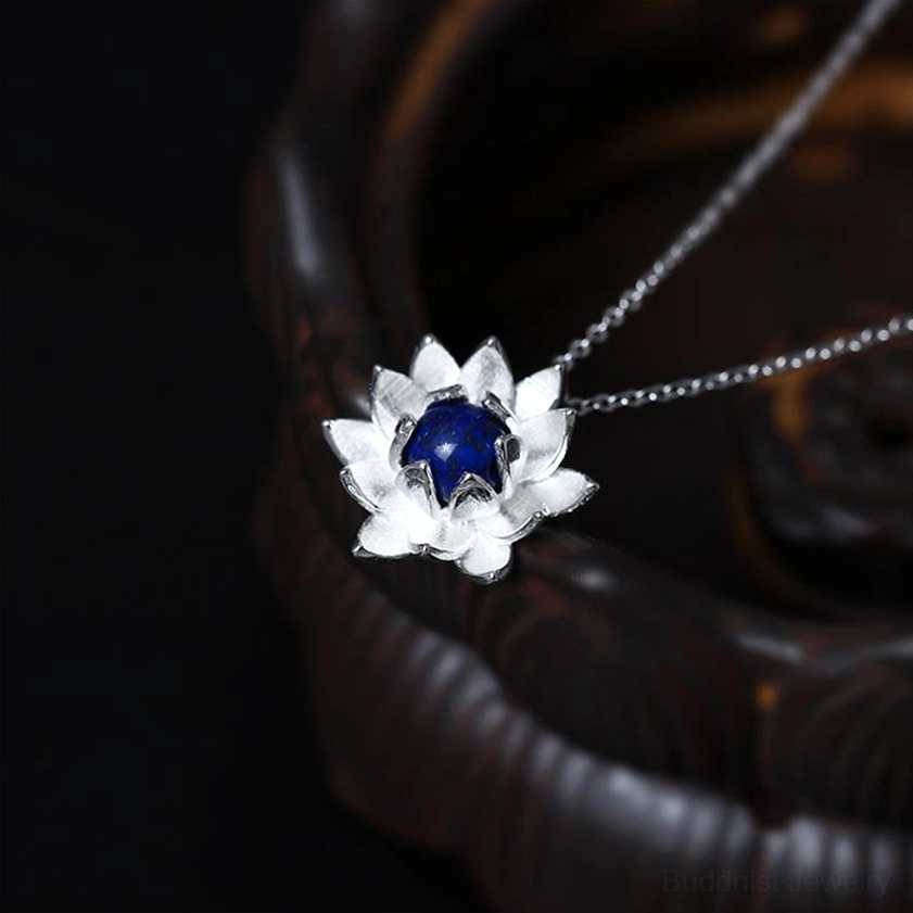 Sterling silver lotus pendant necklace with lapis lazuli stone center, front view showing bright silver petals against dark wooden bowl background