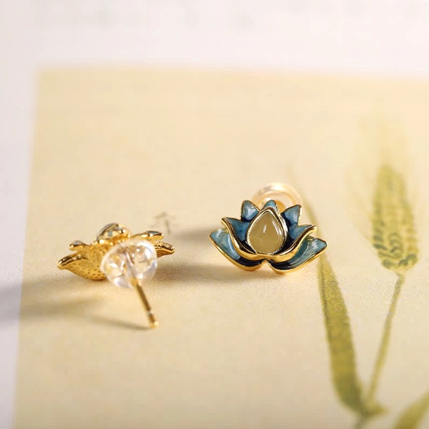 925 sterling silver lotus earrings showing gold-plated posts and clear acrylic nuts on wheat texture background