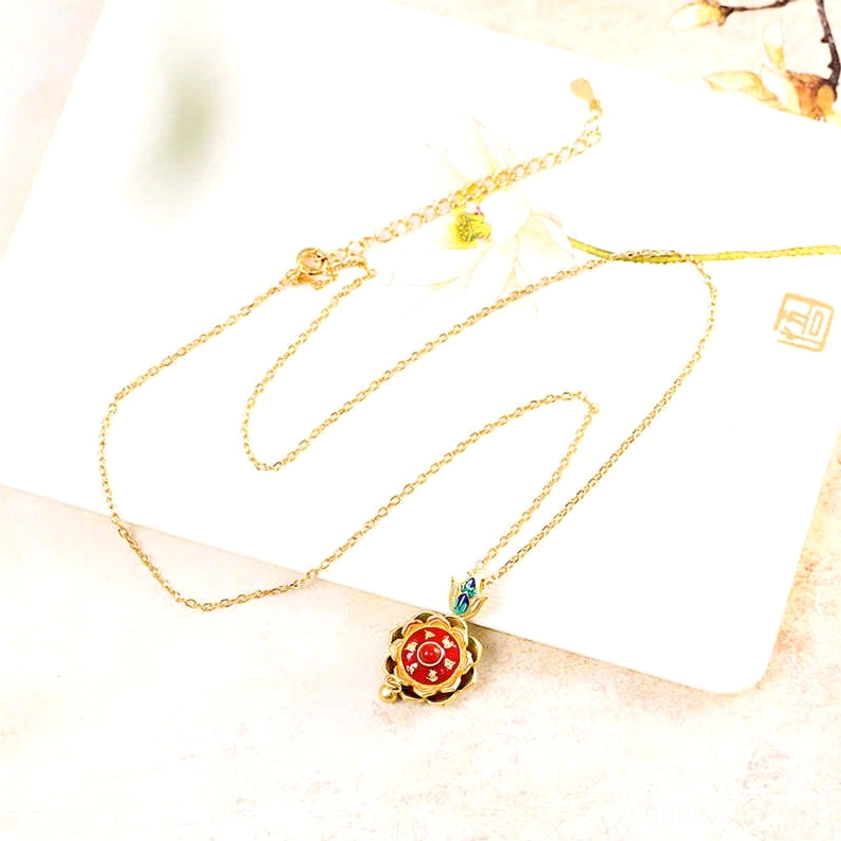Single sterling silver lotus prayer wheel necklace pendant with red enamel center and blue enamel accents on white display board