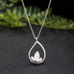 925 sterling silver lotus flower pendant necklace with teardrop hollow frame, close-up top view showing intricate matte lotus design on dark textured background