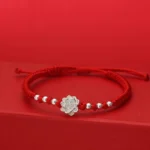 Sterling silver lotus charm with red string bracelet, adjustable knot closure, front flat lay view