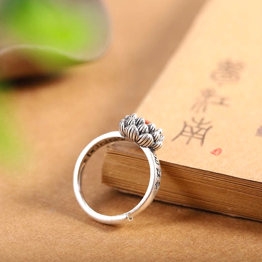 Sterling silver lotus ring back view showing engraved sutra band on antique finish over book pages