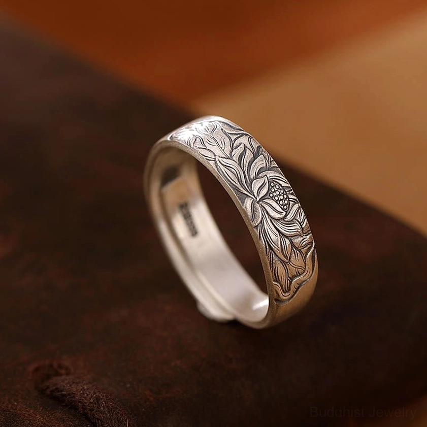 Lotus flower engraved sterling silver adjustable ring three-quarter side view on dark brown leather showing detailed antique silver finish and spiritual lotus design