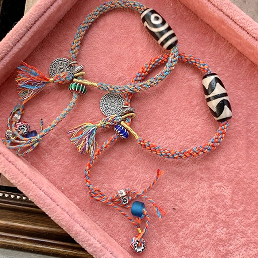 Handmade Nine-Eye Dzi Bead Sterling Silver Om Mani Padme Hum bracelet with red-orange woven rope, silver charm, and blue glass accent bead