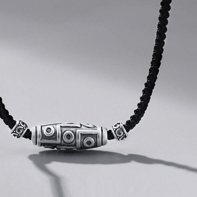 Nine-eye dzi bead buddhist necklace front oblique view with shadow effect highlighting antique silver finish and decorative caps