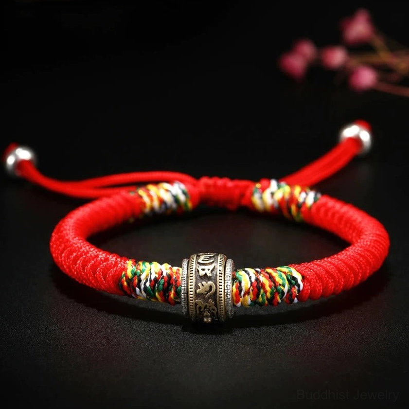 Silver decorated red string bracelet with rotatable silver charm and silver end caps on black background