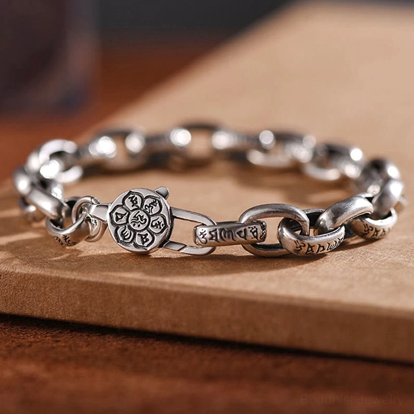 Sterling silver Om Mani Padme Hum six true words buddhist bracelet with engraved mantra charm clasp and curb chain displayed on wooden surface