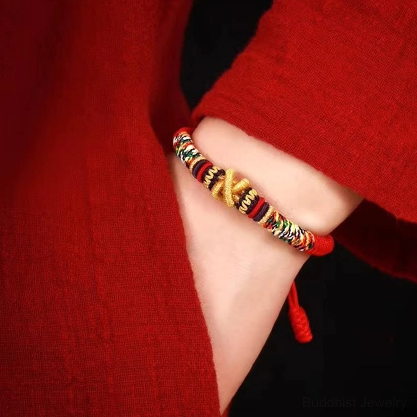 Buddhist faith bracelet worn on wrist showing comfortable fit and mixed color woven design with metal bead