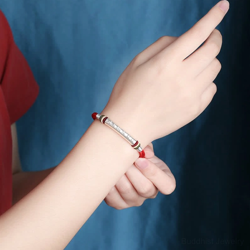Red om mani padme hum Buddhist bracelet worn on left wrist showing natural fit and daily wear styling with silver tube detail