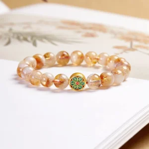 Sterling silver Om Mani Padme Hum citrine bracelet with gold-plated enamel mantra charm displayed on vintage Buddhist book