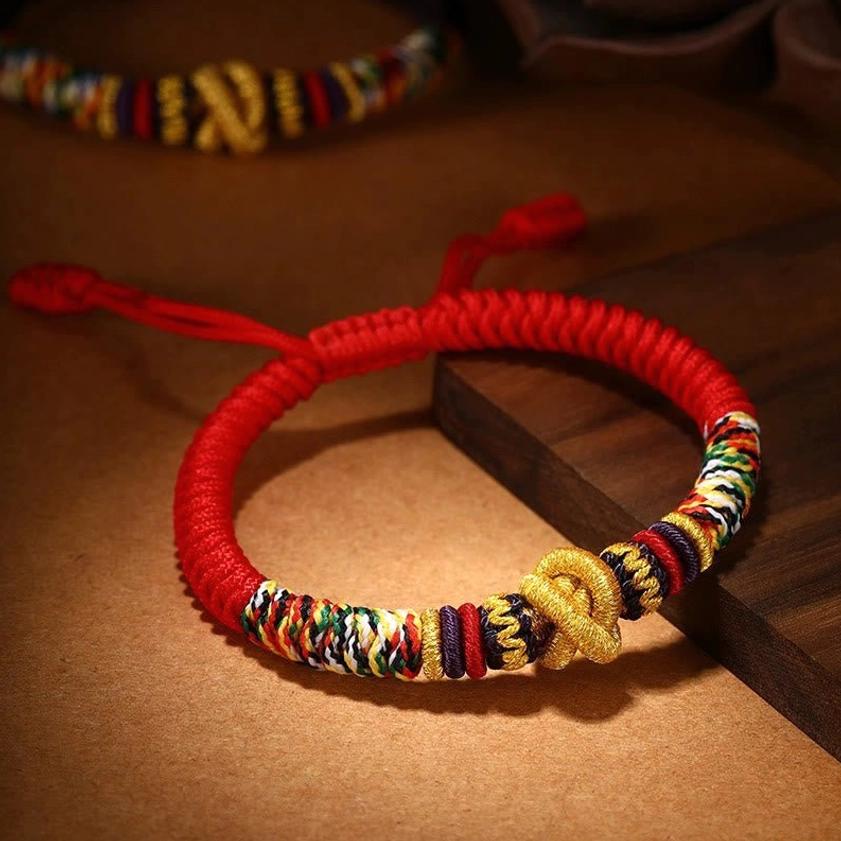 925 Sterling Silver Om Mani Padme Hum King Kong Knot bracelet with red rope and golden knot detail on wooden desktop